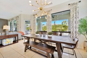 A modern dining area with a wooden table, benches, and a decorative ceiling light fixture. - Bliss: Pool, Spa, Pool Table, Ping Pong, Fire Pit! (Indio)