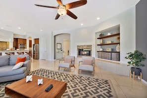 A spacious living area with a sofa, armchairs, a coffee table, and a fireplace. - Bliss: Pool, Spa, Pool Table, Ping Pong, Fire Pit! (Indio)