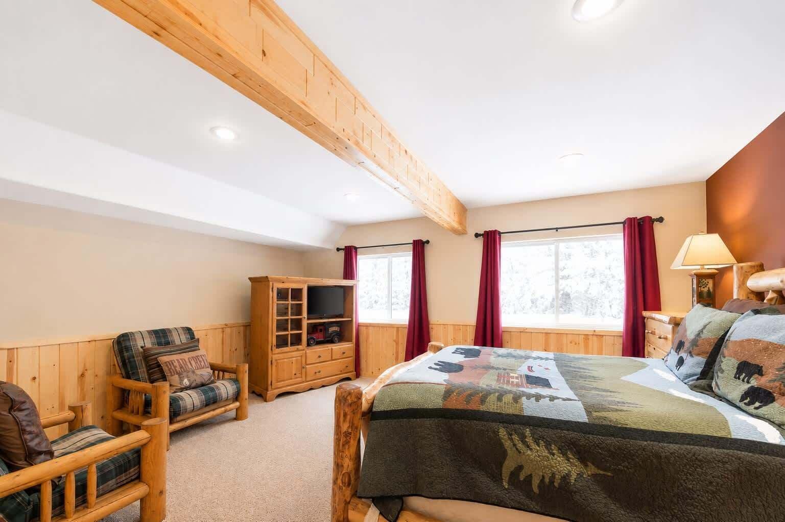 Una habitación con una cama, una silla de madera, un armario y una ventana con cortinas.