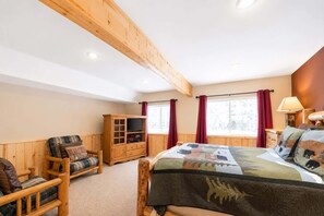 A room with a bed, a wooden chair, a cabinet, and a window with curtains.