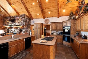 A spacious kitchen with wooden cabinetry, a central island, and a stone wall.