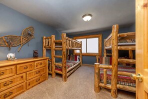A room with bunk beds, a dresser, a window, and a ceiling light.