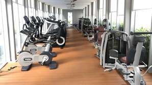 Un gimnasio con máquinas de cardio y equipo de entrenamiento de pesas, ventanas amplias y suelo de madera.