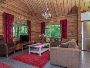 L’intérieur d’une cabane en rondins, avec un téléviseur, un canapé, une table basse et un réfrigérateur.