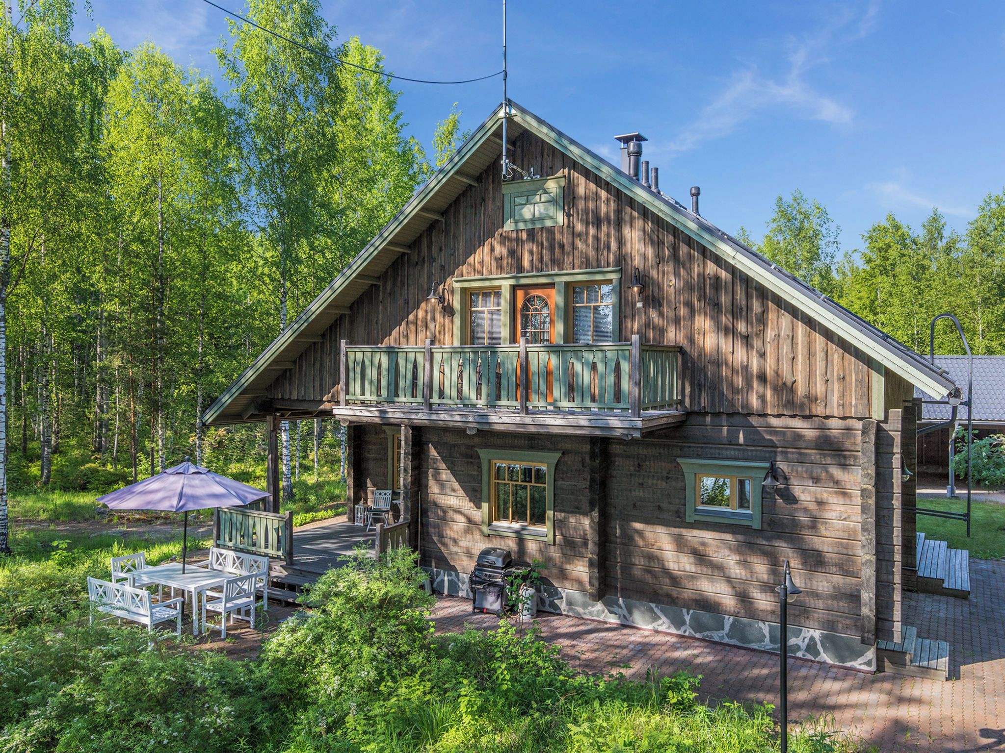 Eine Holzhütte mit Balkon, Sitzgelegenheit im Freien und Grill.