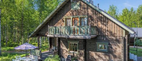 Eine Holzhütte mit Balkon, Sitzgelegenheit im Freien und Grill.