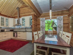 A spacious kitchen with wooden cabinets, a dining table with chairs, and a red rug. - Koivuniemen rouva by Interhome (Mikkeli)