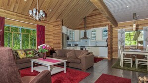 Interior acolhedor de uma cabana de madeira, com sala de estar, cozinha e espaço para refeições.