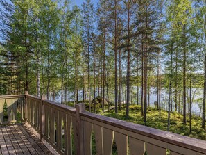 Une terrasse en bois donnant sur une zone boisée avec un lac.