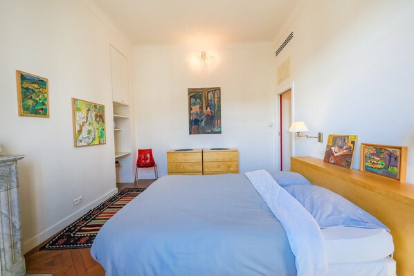 A bedroom with a bed, a dresser, a chair, and artwork on the walls.