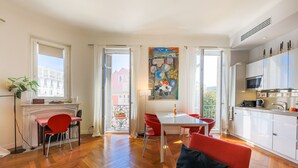 Um apartamento moderno com área de jantar, cozinha e varanda com vista para a cidade.
