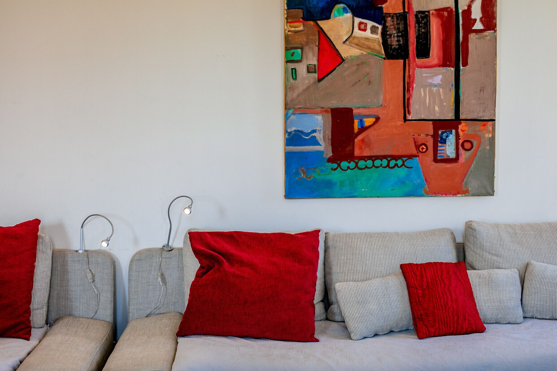 A room with a sofa set and a large abstract painting on the wall.