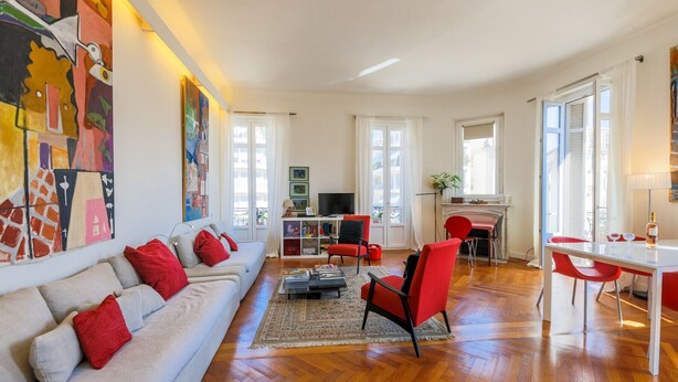 Uma sala de estar ampla com sofá, cadeiras vermelhas, mesa de jantar e lareira.