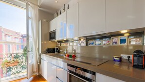 Cozinha moderna com eletrodomésticos de aço inoxidável, uma janela ampla e uma varanda com plantas.