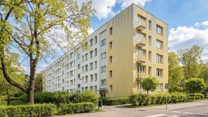 A multi-story residential building with a modern design, featuring balconies and a flat roof.