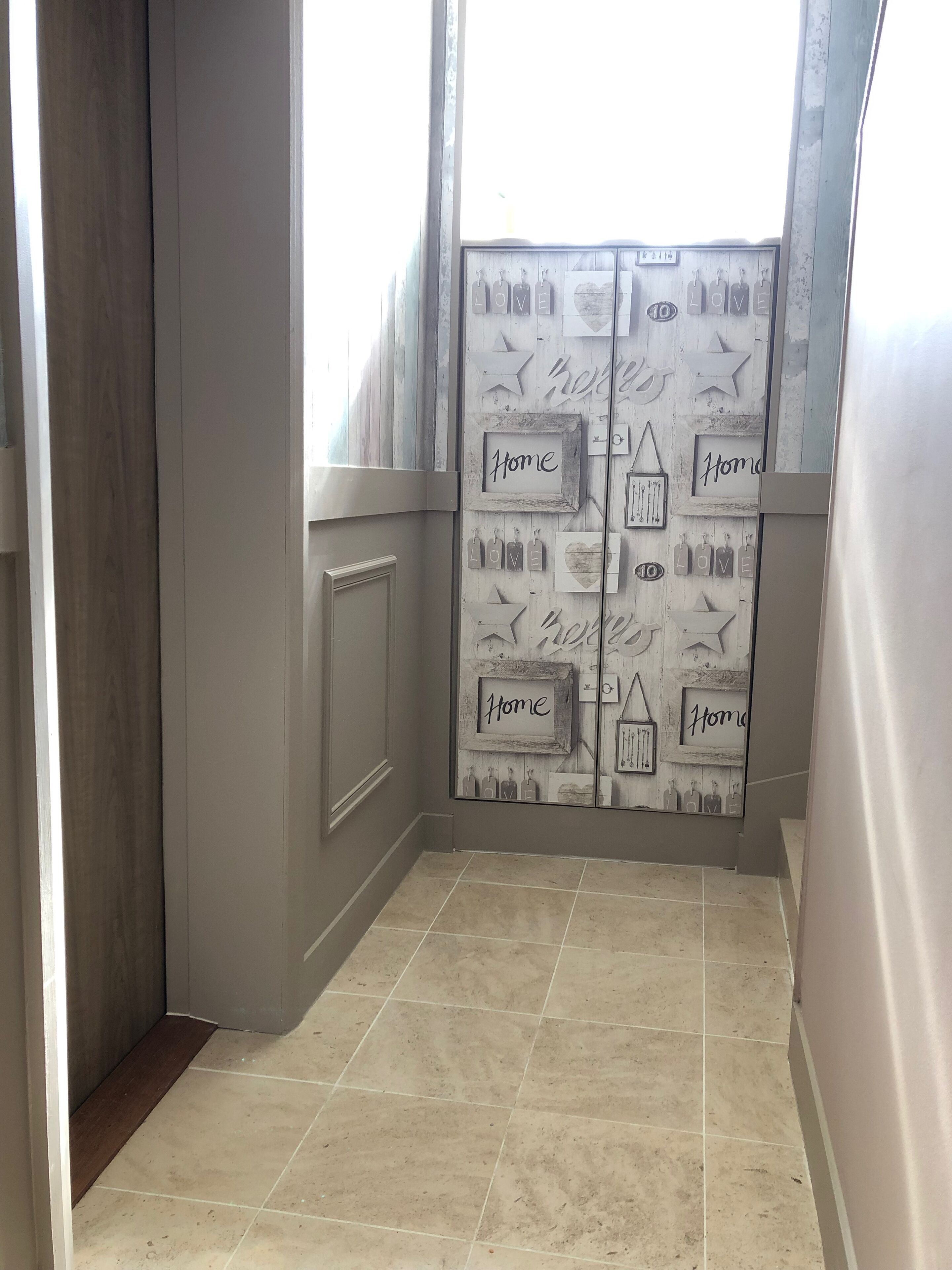 A hallway with a double door featuring decorative elements and the word 'Home' on the glass.