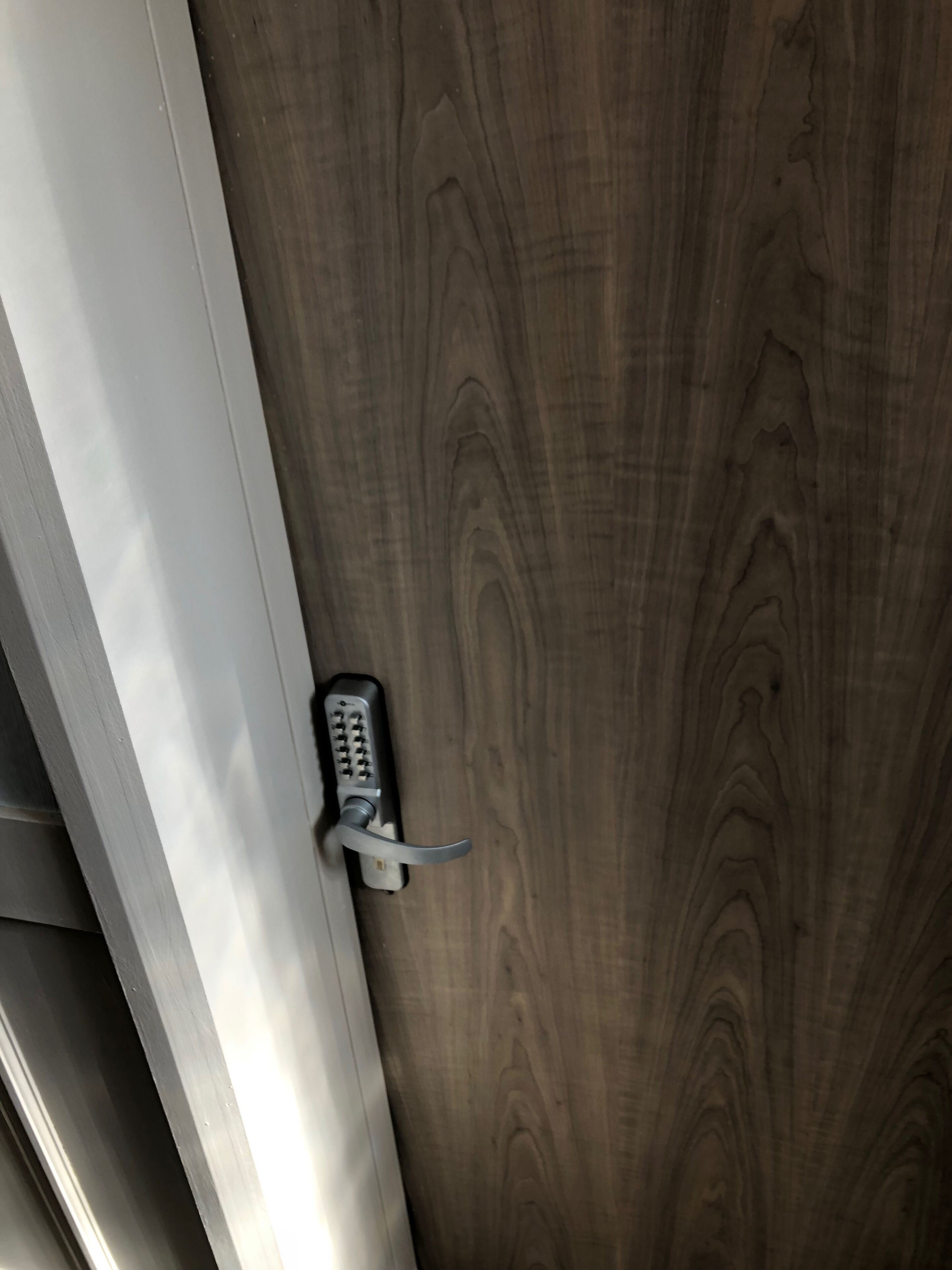 A door with a modern keyless entry lock and a wooden panel.