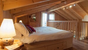 A wooden bedroom with a bed, a nightstand, a lamp, and a window. - Chalet Lisa, ski-in/out, accessible by car (Haute-Nendaz)