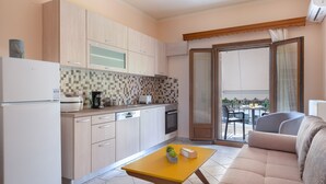 A compact kitchen with modern appliances, a dining area with a yellow table, and a balcony with a view. - Katerina's cozy mountain view apartment (Argostoli)