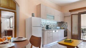A modern kitchen with wooden cabinets, a dining table with chairs, and a small table with a plant. - Katerina's cozy mountain view apartment (Argostoli)