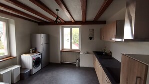 A compact kitchen with a built-in washer and dryer, wooden cabinets, and a window providing natural light. - Large gite with 9 places (Lièpvre)