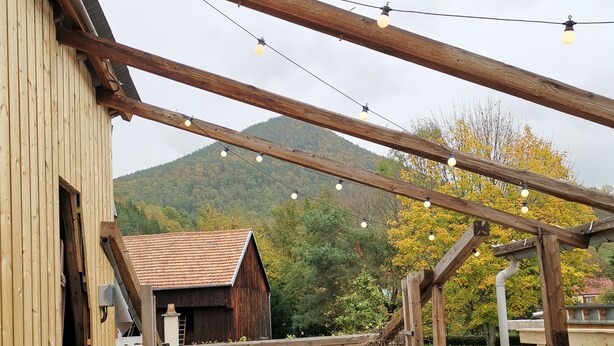 A rustic wooden building with a sloped roof, a wooden dock extending into a body of water, and a mountainous backdrop. - Large gite with 9 places (Lièpvre)