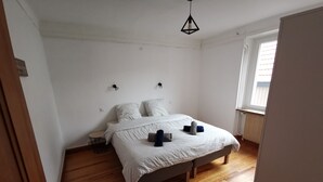 A bedroom with a bed, wooden flooring, a radiator, and a window with blinds. - Large gite with 9 places (Lièpvre)