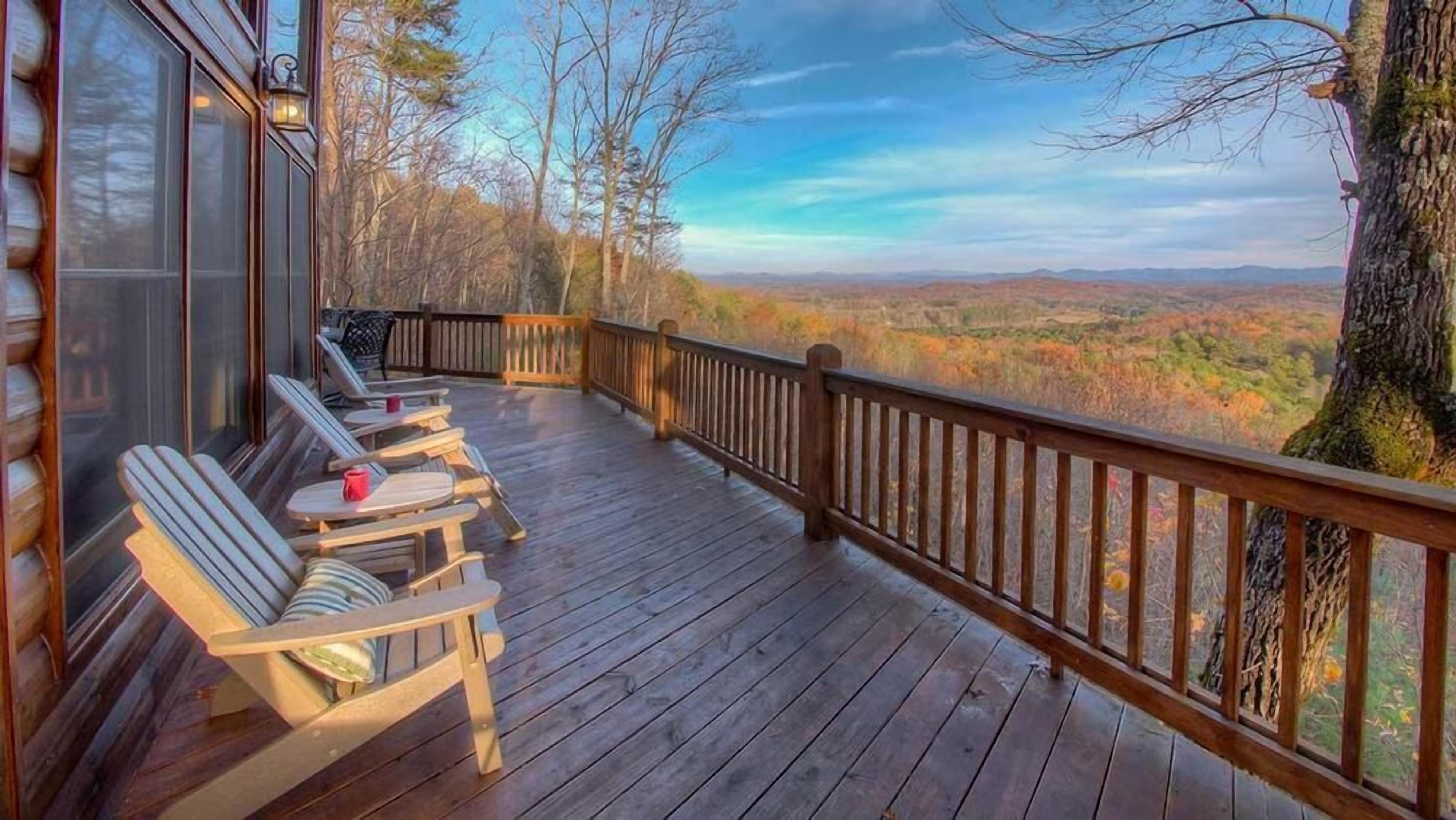 A wooden deck with outdoor seating and a view of a forested landscape.