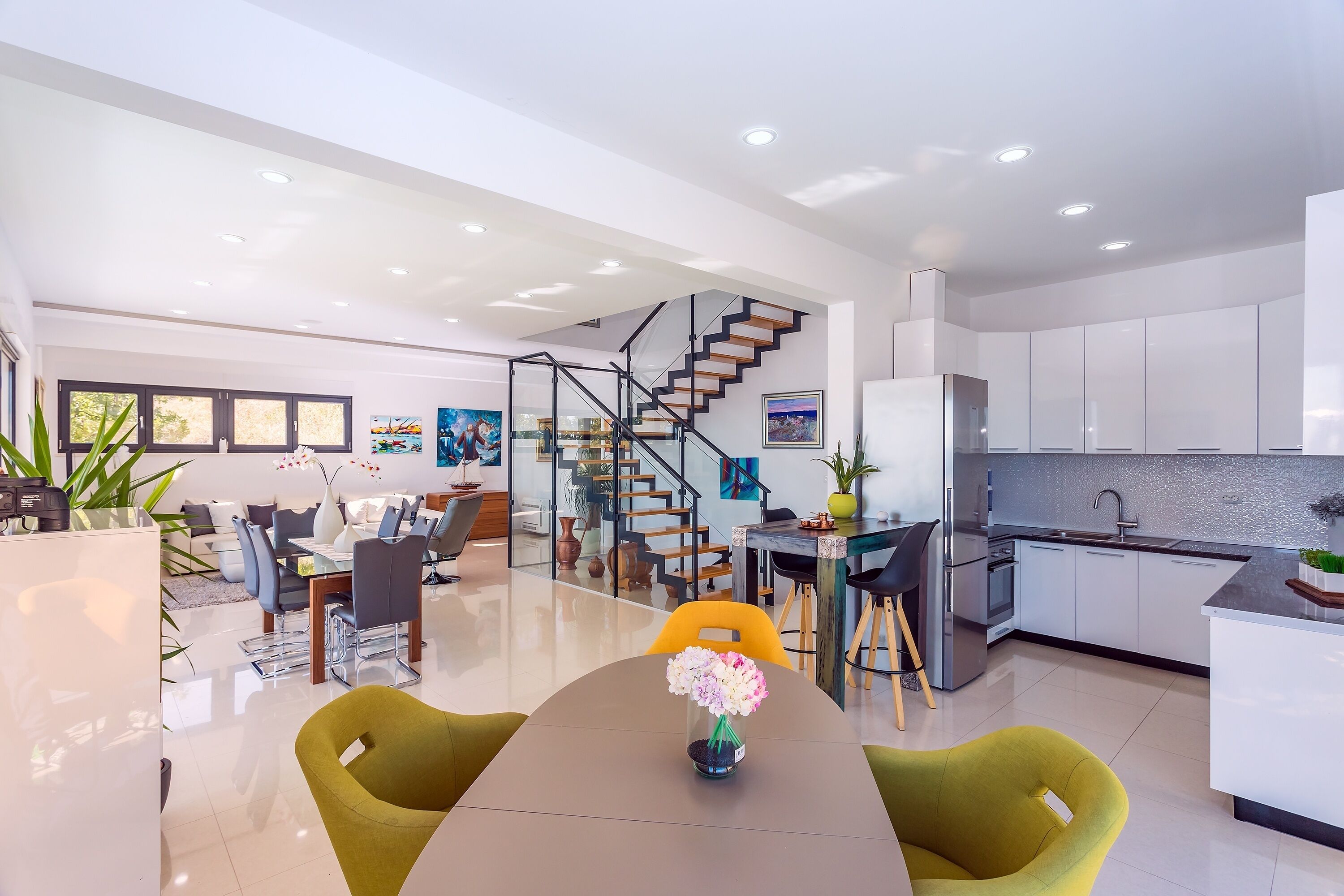 Un espace de vie moderne à aire ouverte comprenant une salle à manger, une cuisine et un escalier.