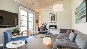 Una sala de estar moderna con un sofá gris, un sillón azul y una mesa de centro de vidrio.