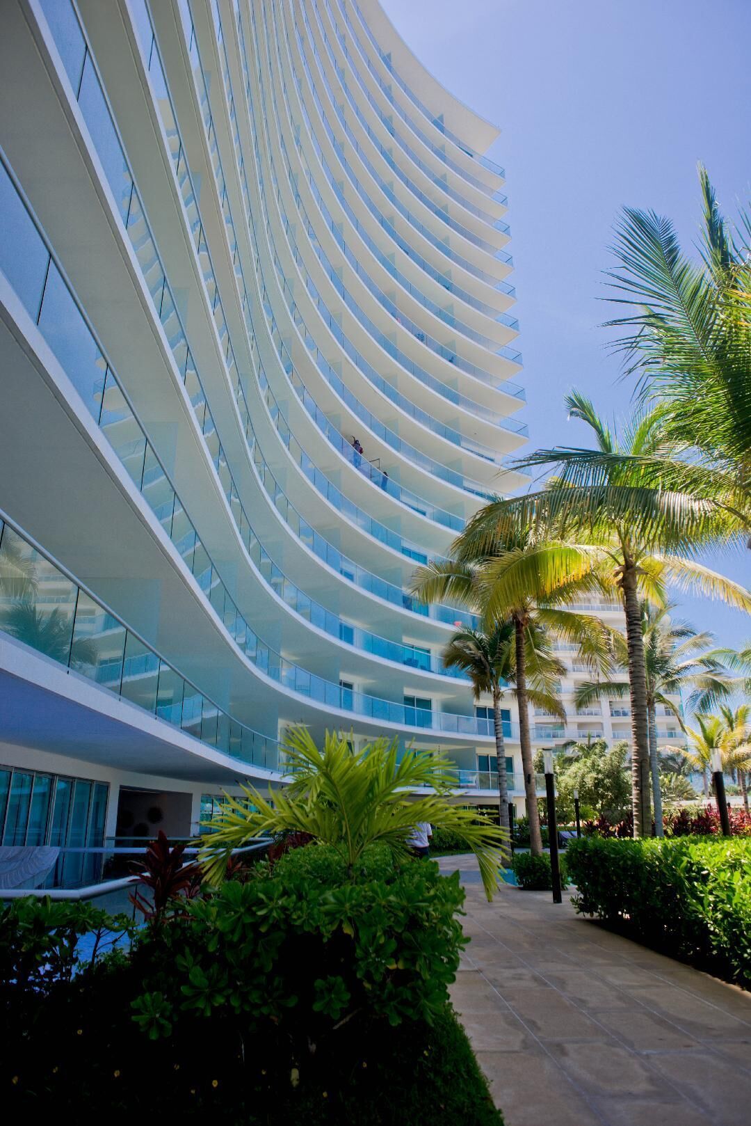 Un hotel moderno con balcones curvos y una zona de piscina.