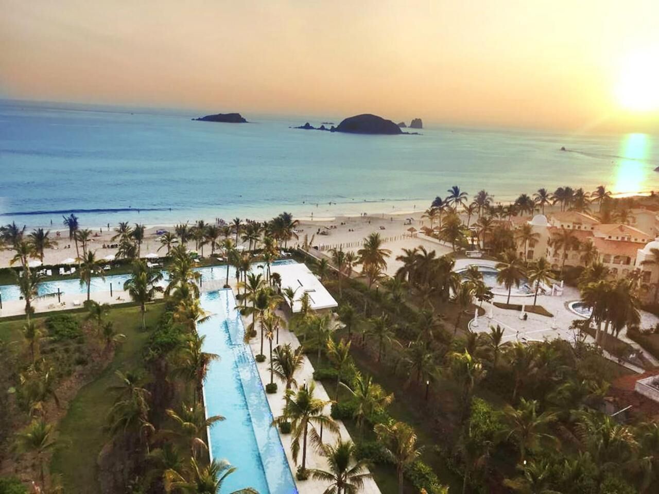 A resort with a pool, palm trees, and a beach view.