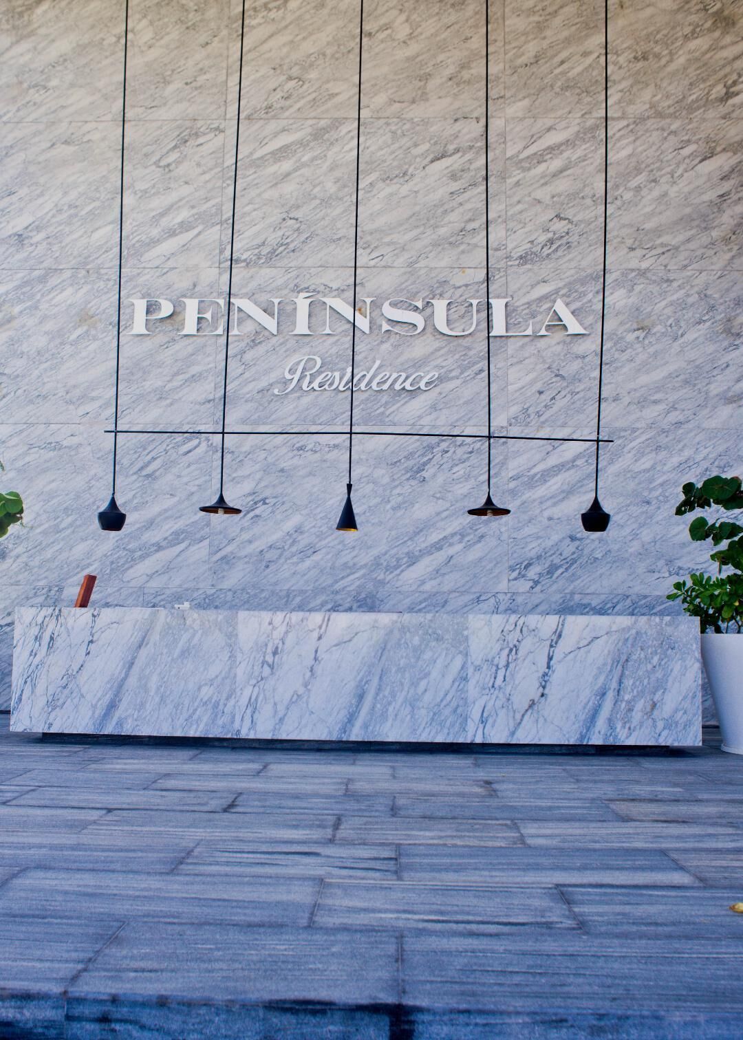 A reception area with a marble wall and a reception desk.