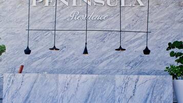 A reception area with a marble wall and a reception desk.
