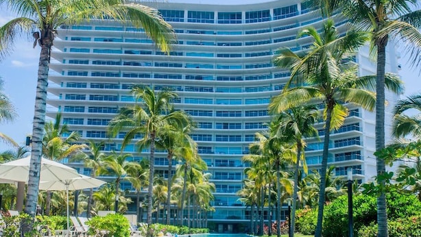 Un gran hotel con piscina rodeado de palmeras.
