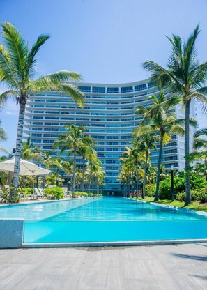 Un gran hotel con piscina rodeado de palmeras.