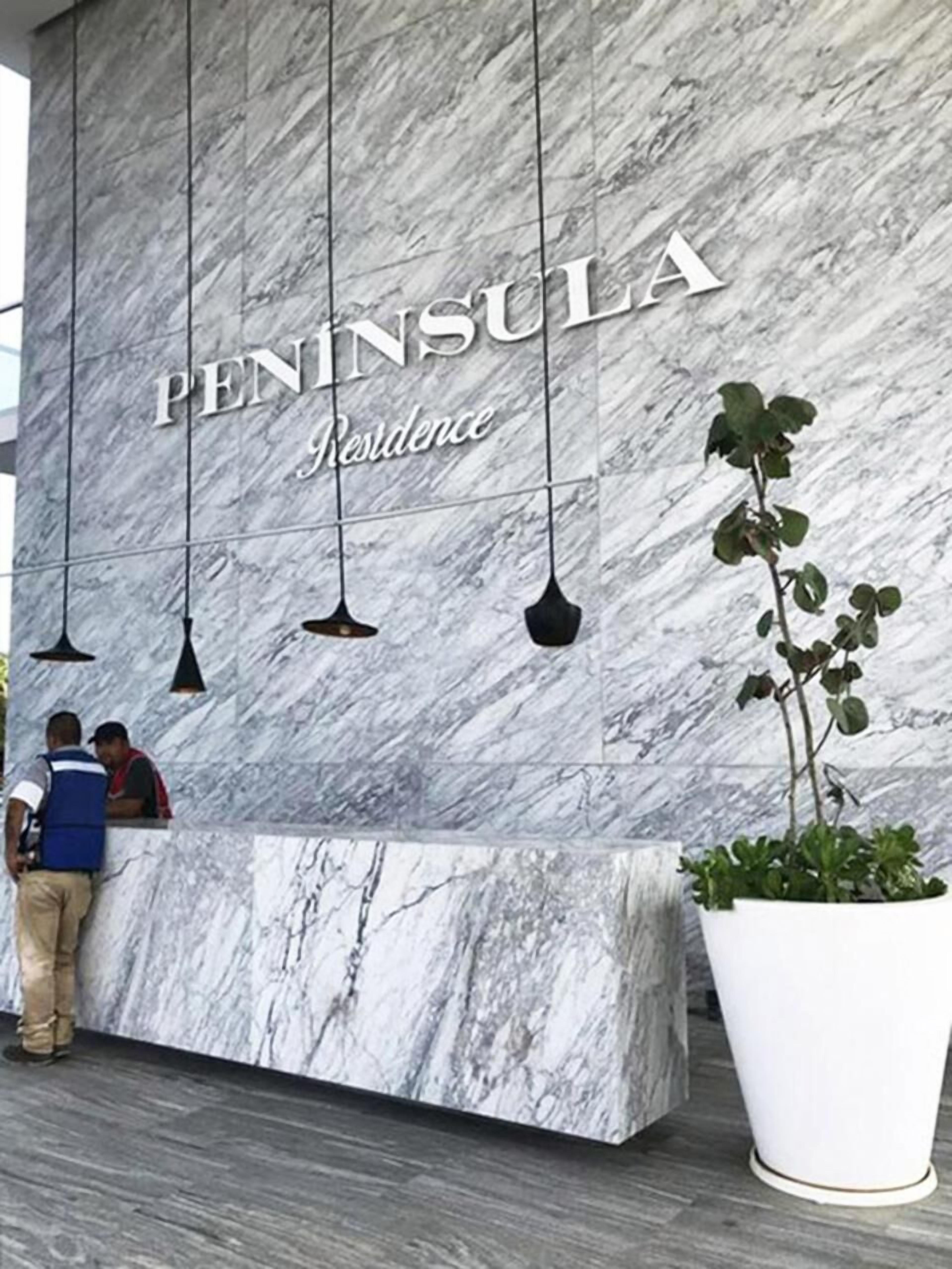 Una recepción con pared de mármol y una planta grande en maceta.