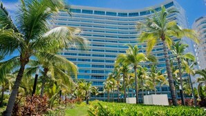 Un hotel moderno con fachada curva, rodeado de palmeras y exuberante vegetación.