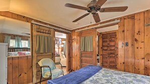 A wooden cabin bedroom with a bed, a chair, and a ceiling fan. - Walk to Marina: Cute Gilford Cottage w/ Grill (Gilford)