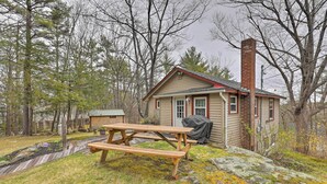A small cabin with a picnic table and a covered grill area. - Walk to Marina: Cute Gilford Cottage w/ Grill (Gilford)