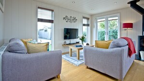 En moderne stue med to grå sofaer, et træbord og et fladskærms-tv.