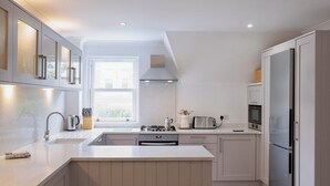 A modern kitchen with a central island, a built-in oven, a microwave, and a refrigerator. - 3 bedroom accommodation in Fowey (Fowey)