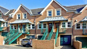 A row of brick houses with green railings and a car parked in front. - 3 bedroom accommodation in Fowey (Fowey)
