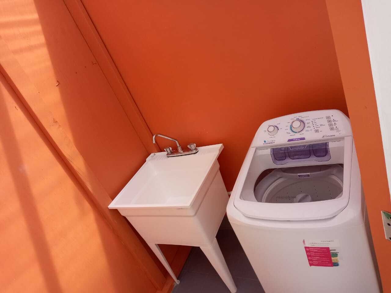 Un baño pequeño con un lavabo blanco y una lavadora de carga frontal.