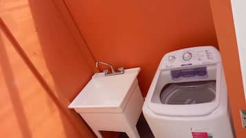 Un baño pequeño con un lavabo blanco y una lavadora de carga frontal.