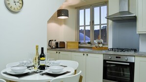 Une cuisine moderne avec des meubles blancs, une cuisinière à gaz et un coin repas comprenant une table ronde et des chaises.