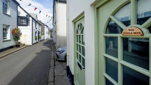 A narrow street lined with white buildings, including a pub named 'The Middle Deck' with a green door and window frames. - 2 bedroom accommodation in Fowey (Fowey)