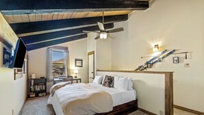 Una camera da letto con una testiera in legno, una ventola a soffitto, una libreria e una decorazione murale a tema sciistico.