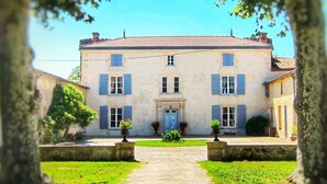 A two-story building with a symmetrical facade, a central entrance with a door, and a small garden area in front.