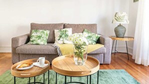 En stue med en sofa, to sofaborde, en lampe og en vase med blomster.